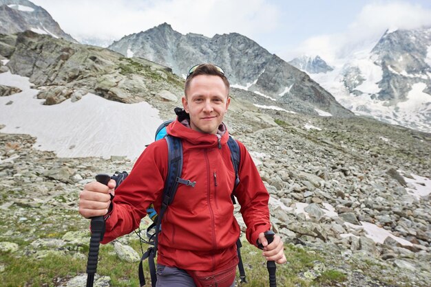 Tourist posing using trakking sticks mountains on\
background