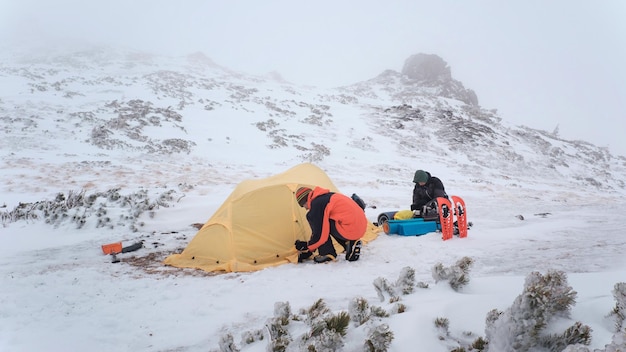 Tourist put up tent in winter mountains while hiking
