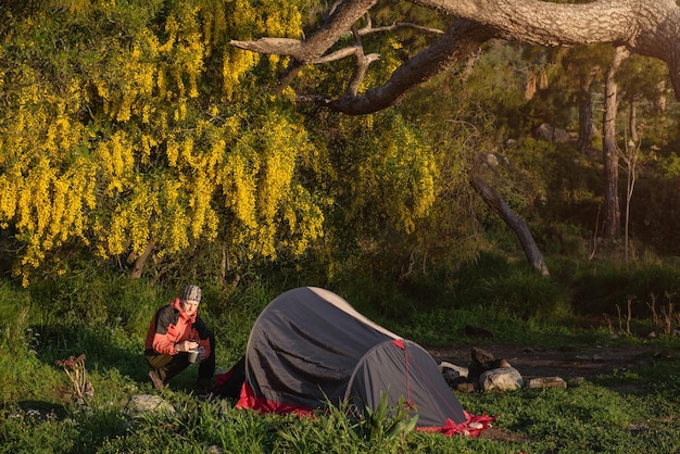 Tourist putting tent and cooking food in a camping in spring forest