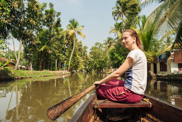 Tourist relaxing on alleppey backwaters and enjoying beautiful
view landscape woman sitting on the boat at meditation pose kerala
india