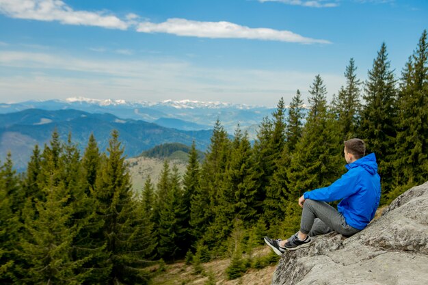 A tourist sits on cliff and looks into the distance