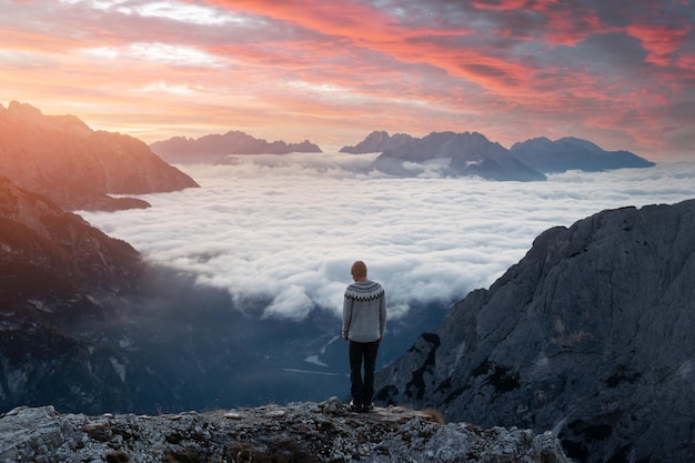 A tourist stay over the fog at the edge of a cliff in the Dolomites mountains Location Auronzo rifugio in Tre Cime di Lavaredo National Park Dolomites Trentino Alto Adige Italy