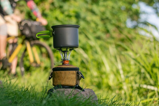 Tourist stove gas for camping and recreation on the background of nature A male cyclist is in the background