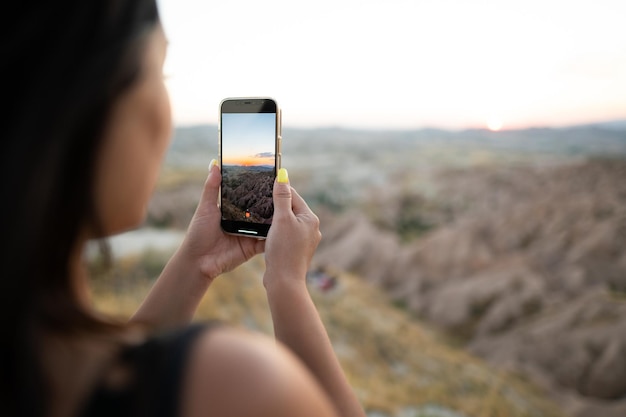 観光客が携帯電話で山の夕日の写真を撮る