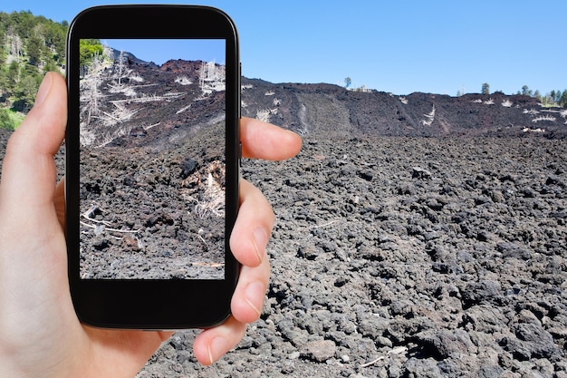 Tourist taking photo of lava flow on slope of Etna