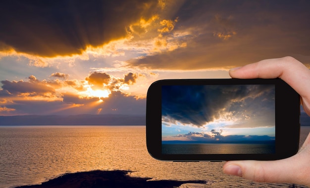 Tourist taking photo of sundown on Dead Sea