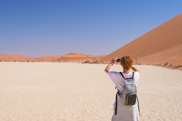 Tourist taking photo with smart phone at Sossusvlei, Namib desert, Namib Naukluft National Park.