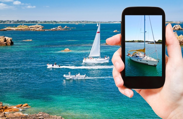 Tourist taking photo of yacht near Brittany