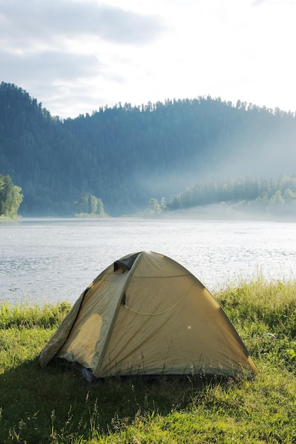 Tourist tent on river bank Camping tent near mountain river Local tourism weekend at nature