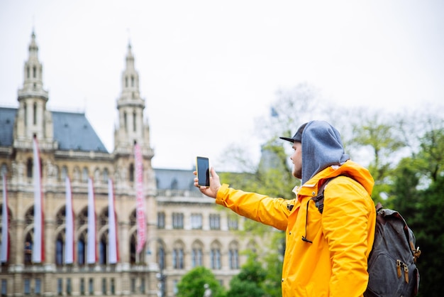 Tourist traveler man taking picture on phone vienna city hall on background