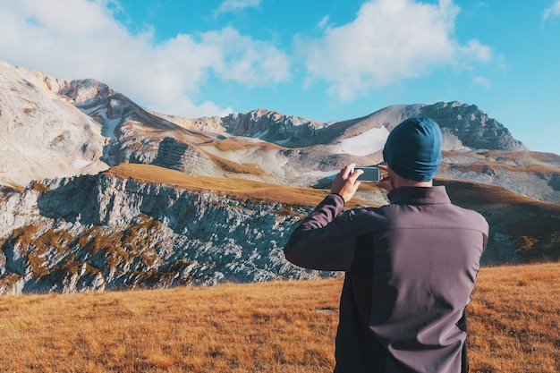 Tourist traveler photographs mountains covered with clouds on a smartphone