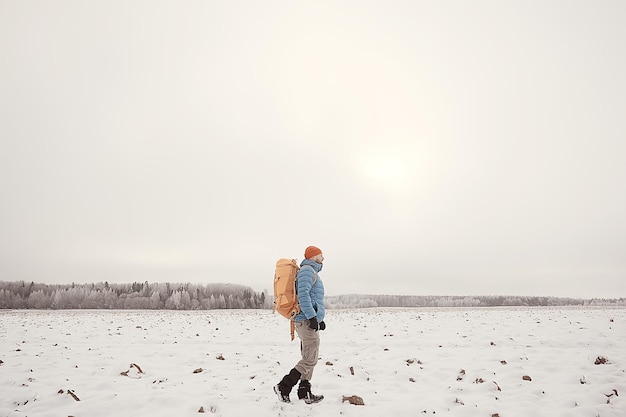 туристический вид со спины / мужчина с рюкзаком идет по зимнему лесу, вид на уходящий