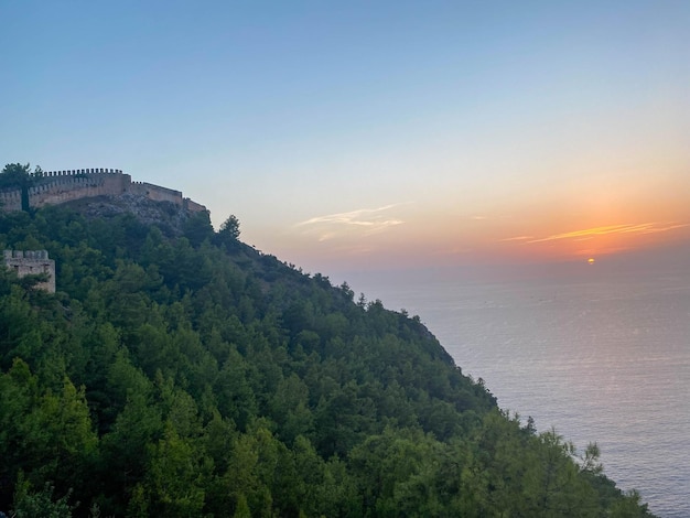 Tourist view from the mountain from a height to the peninsula seashore and green trees at sunset