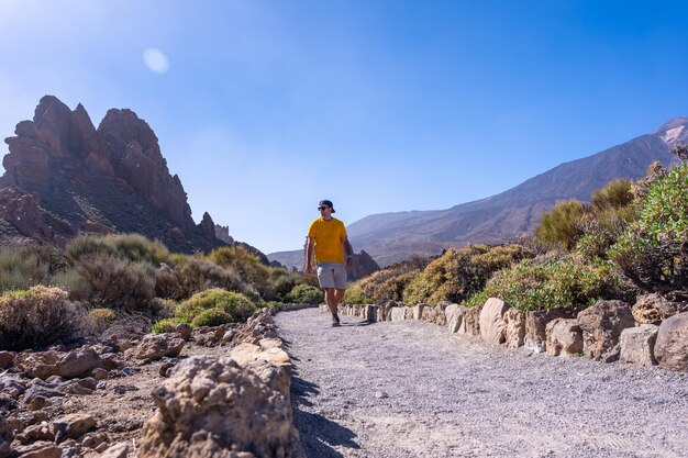 A tourist walking on the path between Roques de Gracia and Roque Cinchado in the natural area of Teide in Tenerife Canary Islands