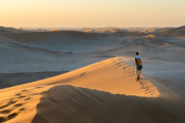 Tourist walking on the scenic dunes of Sossusvlei, Namib desert, Namibia.