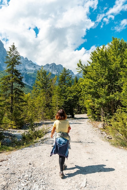 Турист, идущий по тропе долины Валбона среди деревьев Национальный парк Тет Албанские Альпы Албания