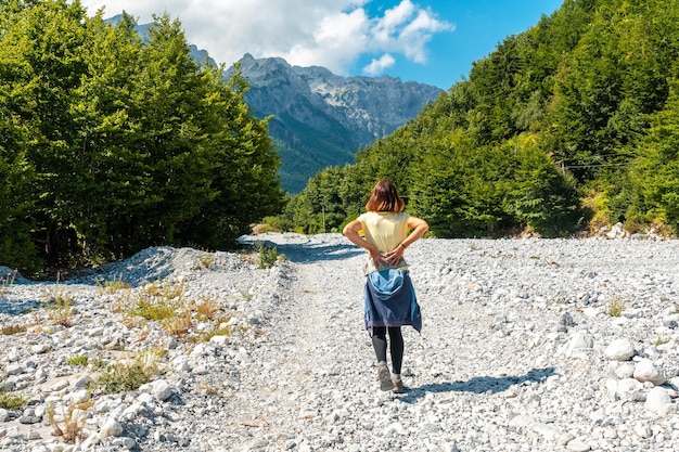 A tourist walking on the Valbona Valley trail alongside trees Theth National Park Albanian Alps Albania