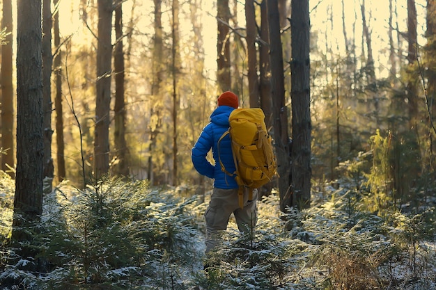 冬の森の観光客/男は森、雪、木々のある冬の風景を背景に旅行します