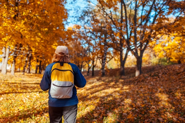 Tourist with backpack walking in autumn forest 