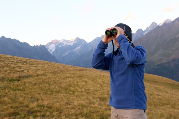 Turista con il binocolo alla ricerca in una zona montuosa in georgia