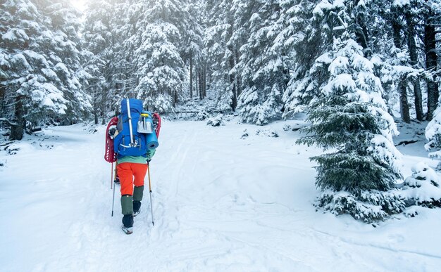 冬の山で夜を過ごすための機器を持つ観光客