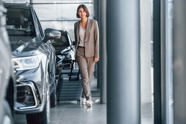 Tourist with lugagge Woman is indoors near brand new automobile indoors