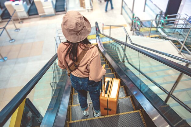 Tourist with luggage down the escalator at airport.