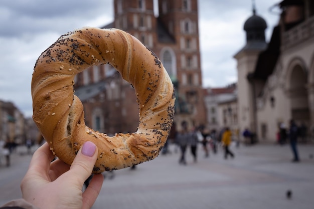 写真 ポーランドの伝統料理のスナックを食べている女性観光客が市場広場を歩いています