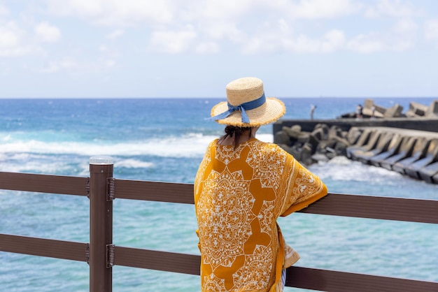 観光客の女性が夏に海の景色を楽しんでいます