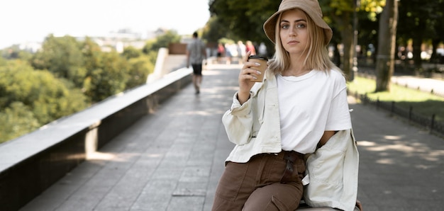 ヨーロッパの都市の観光客の女性、ヨーロッパの観光。彼女の手にコーヒーを持って公園で若い女性。