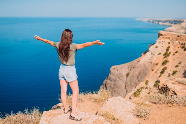 Donna turistica all'aperto sul bordo della scogliera in riva al mare