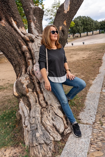 Tourist woman resting on the trunk of a very old tree in the village of Frias Burgos