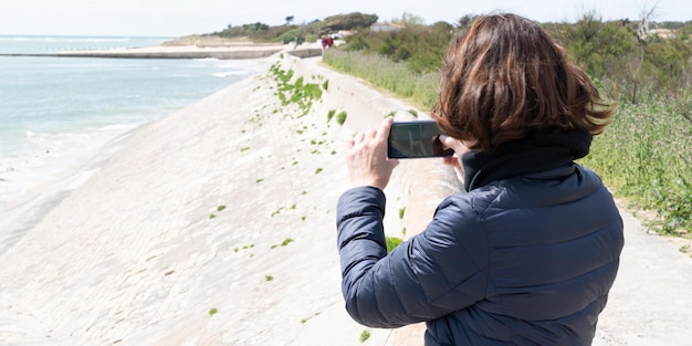 Photo tourist woman taking a picture photo on their phone at the beach