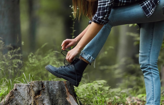 A tourist woman tying her shoelace while preparing for hiking in the forest