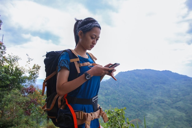 A tourist woman uses a smartphone in the mountains