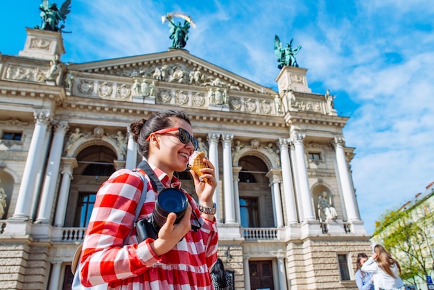 유럽 도시 한가운데에서 사진 카메라와 아이스크림을 들고 있는 관광 여성
