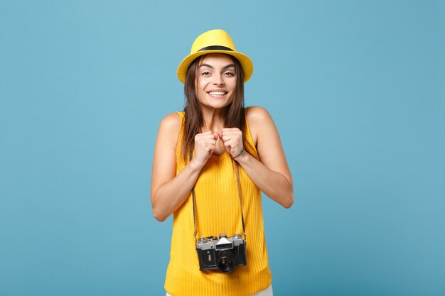 青の写真カメラと黄色の夏のカジュアルな服と帽子の観光客の女性