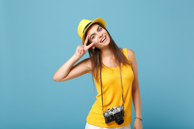 tourist woman in yellow summer casual clothes and hat with photo camera on blue