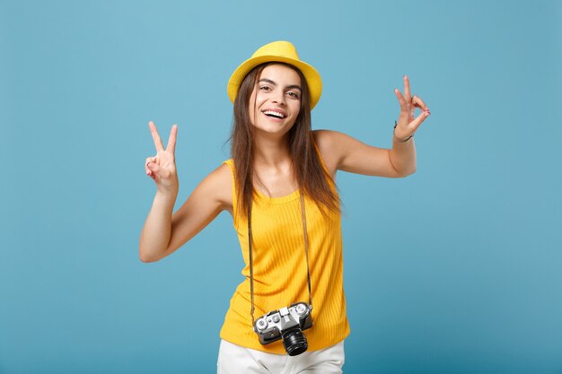 青の写真カメラと黄色の夏のカジュアルな服と帽子の観光客の女性