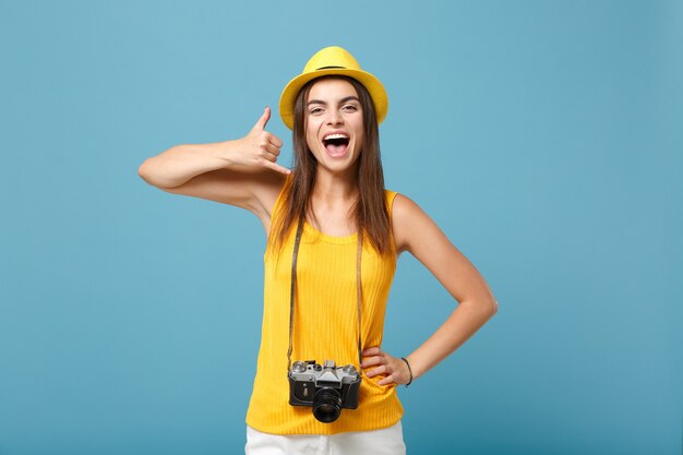 青の写真カメラと黄色の夏のカジュアルな服と帽子の観光客の女性