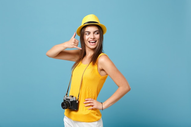 青の写真カメラと黄色の夏のカジュアルな服と帽子の観光客の女性