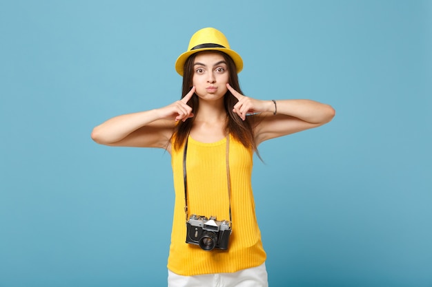 tourist woman in yellow summer casual clothes and hat with photo camera on blue