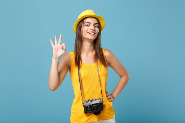 青の写真カメラと黄色の夏のカジュアルな服と帽子の観光客の女性