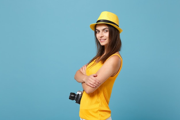 tourist woman in yellow summer casual clothes and hat with photo camera on blue