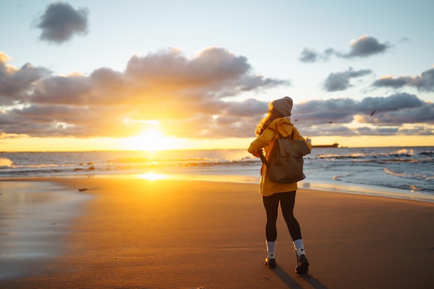 Турист в желтой куртке наслаждается морским пейзажем на закате Образ жизни путешествие природа активная жизнь