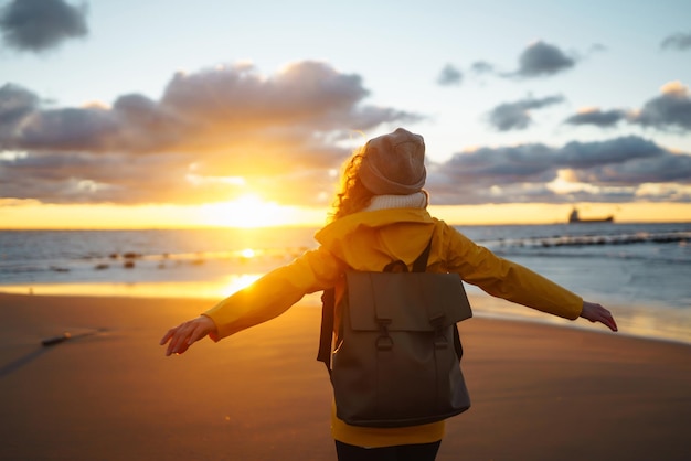 Tourist in yellow jacket enjoying sea landscape at sunset Lifestyle travel nature active life