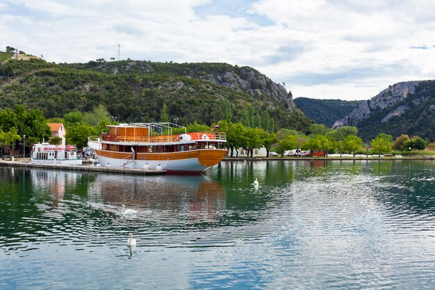 Touristic boat and swans in Skradin, Croatia. Horizontal shot