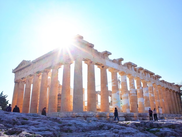 Photo tourists at acropolis of athens against clear blue sky on sunny day