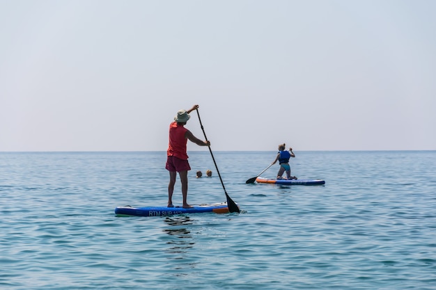 観光客は、穏やかな海の表面でボード（sup）をrowいでいます。