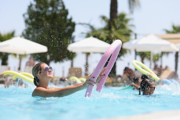 Туристы занимаются водной аэробикой в бассейне на курортных развлечениях и спортом в отелях.
